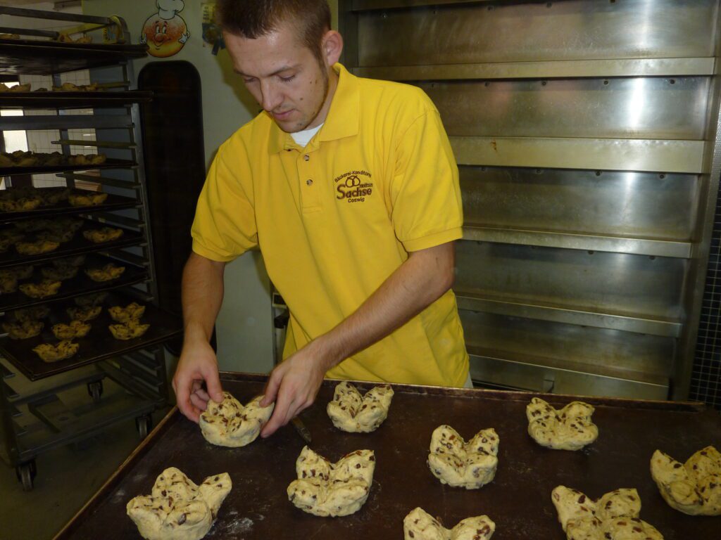 Bäcker formt mit den Händen Teigstücke für Gebäck in der Backstube der Bäckerei Sachse in Coswig
